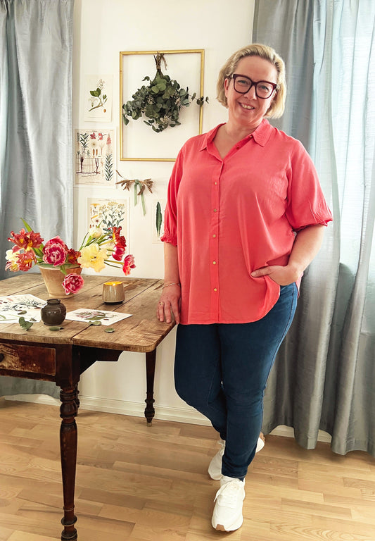 En skjønn rosa bluse med en klassisk krage og gullfargede knapper. Korte ermer med en romantisk strikk. Dette er en løs og ledig bluse som er riktig fin til jeans. Fra Zoey.