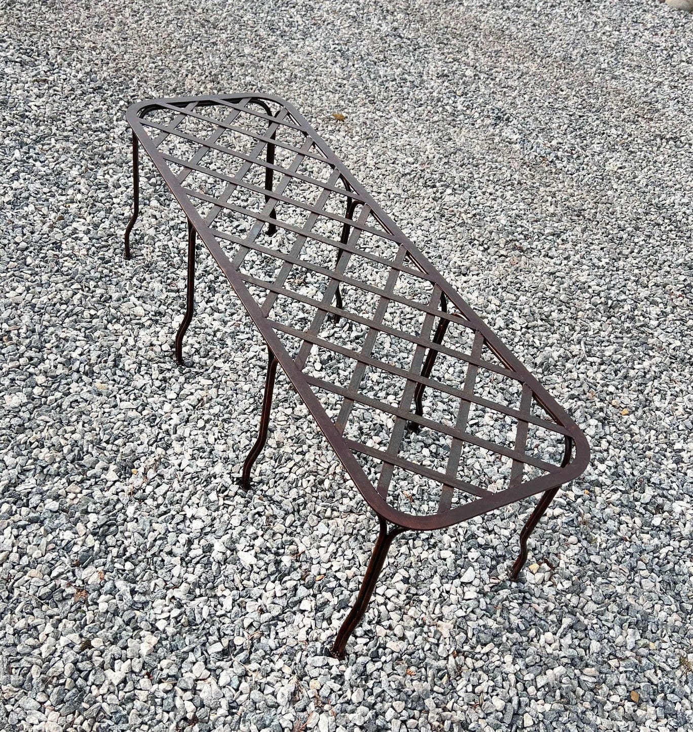 Håndlaget vakker hagebenk i jern. Den vil med tiden få en overflate med rust som smelter fint inn i hagen. Like fin å sitte på som å bruke til krukker og blomsterarrangement.