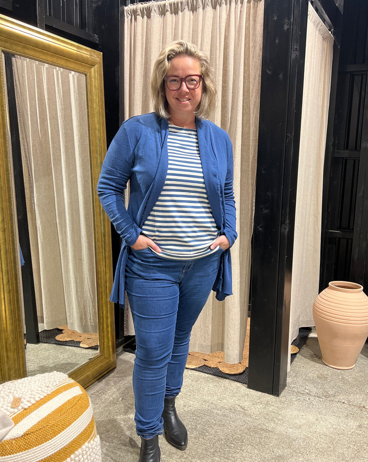 Den mykeste merinoullen som ikke klør og holder på passformen! En lett innsvingt tynnstrikket lang cardigan i denim blue  med en lekker rå kant i front. 100% merinoull fra By Basics.