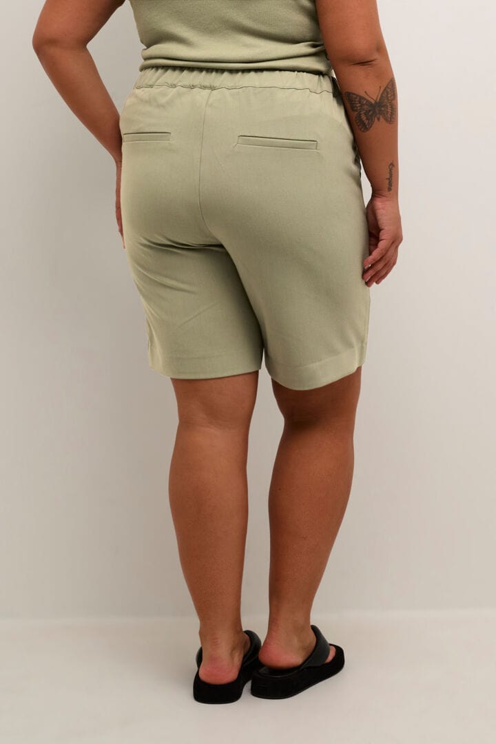 Endelig er KCSakira shortsen her! Dette er en perfekt city shorts i fargen vetiver som er litt mer dresset. Shortsen fra Kaffe Curve går til knærne, har strikk bak for beste comfort og lommer bak og i sidene.