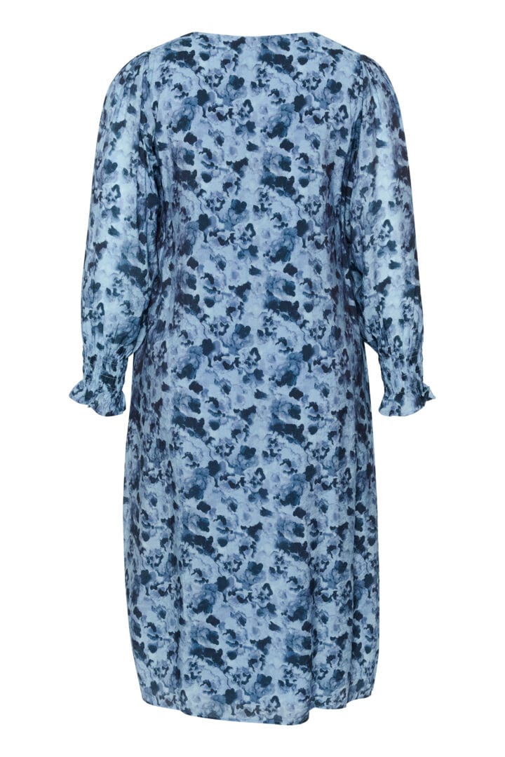 En frisk og herlig kjole i rett fasong med blått mønster og v-hals. Små rynker på skulderne som gir et løft og strikk i ermer så lengden kan justeres enkelt. En kjole som er klar for eventyr.  Bakside fra Kaffe Curve.