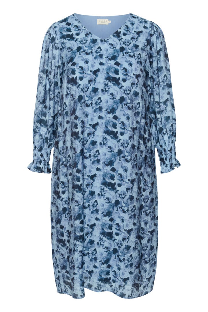 En frisk og herlig kjole i rett fasong med blått mønster og v-hals. Små rynker på skulderne som gir et løft og strikk i ermer så lengden kan justeres enkelt. En kjole som er klar for eventyr.  Fremside, fra Kaffe Curve.