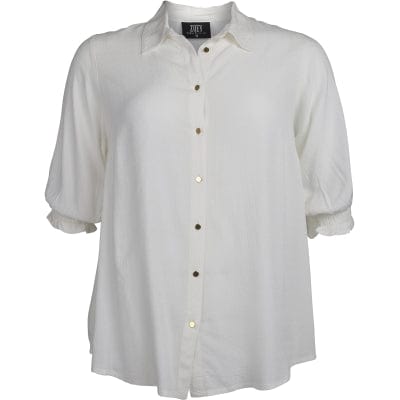 En nydelig off-white bluse med en klassisk krage og gullfargede knapper. Korte ermer med en romantisk strikk. Dette er en løs og ledig bluse som er riktig fin til jeans, fra Zoey stormote.