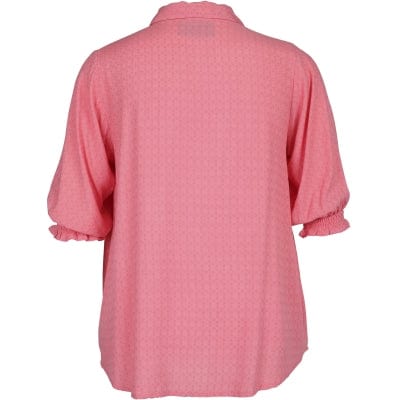 En nydelig rosa bluse fra Zoey stormote med en klassisk krage og gullfargede knapper. Korte ermer med en romantisk strikk. Dette er en løs og ledig bluse som er riktig fin til jeans.
