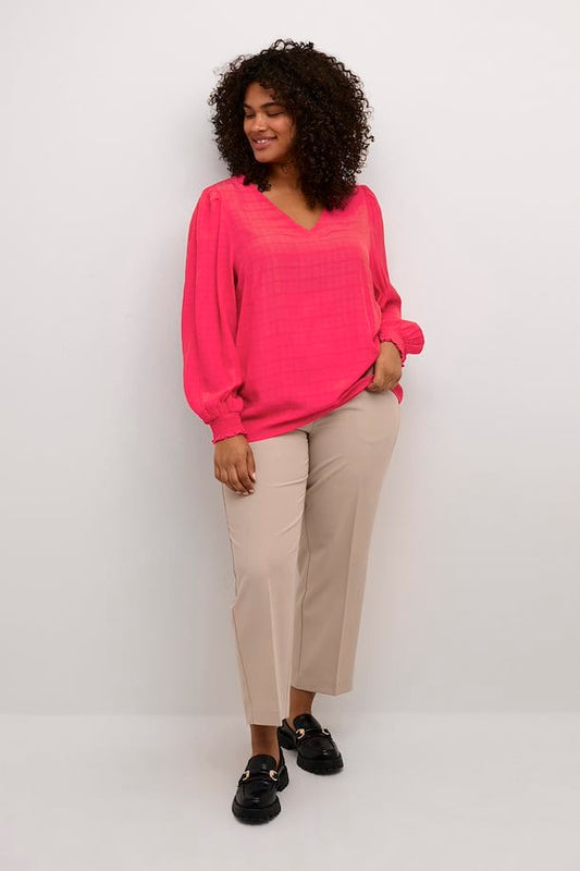 En herlig rosa bluse fra Kaffe Curve med lange ermer og strikk. Blusen har et vevet mønster, v-hals og små puffer på skulderne som en fin detalj. Kombiner med jeans eller dressbukse.