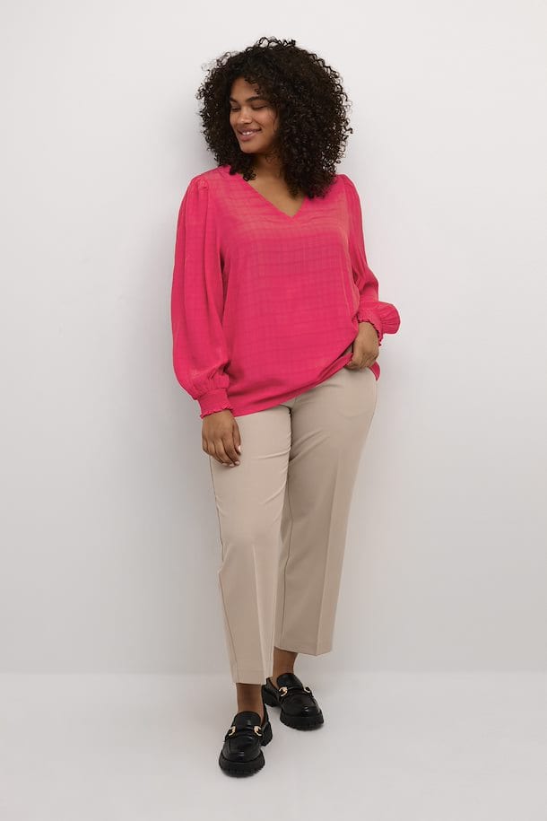 En herlig rosa bluse fra Kaffe Curve med lange ermer og strikk. Blusen har et vevet mønster, v-hals og små puffer på skulderne som en fin detalj. Kombiner med jeans eller dressbukse.